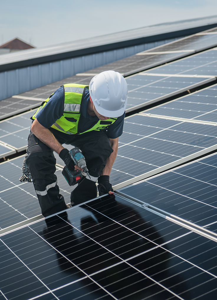 A worker installing solar panels on a commercial roof
