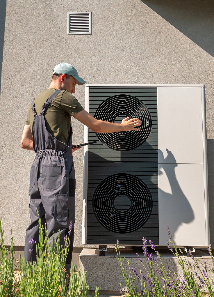 A contractor installing a heat pump outside a home